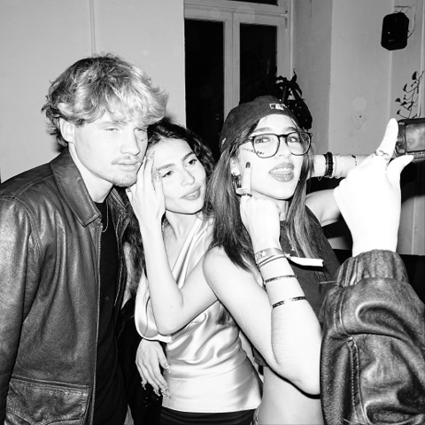 Three guests posing close together for a flash photograph, one holding a small camera into the frame.